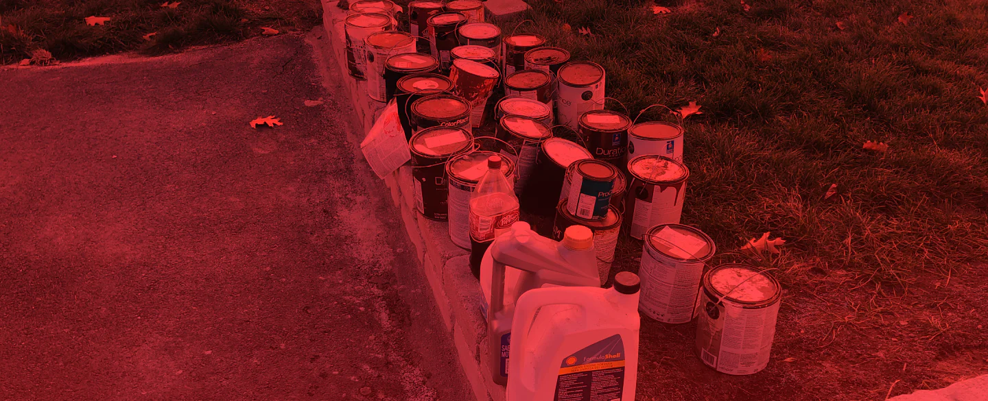 paint buckets junk outside of a house with the grass around